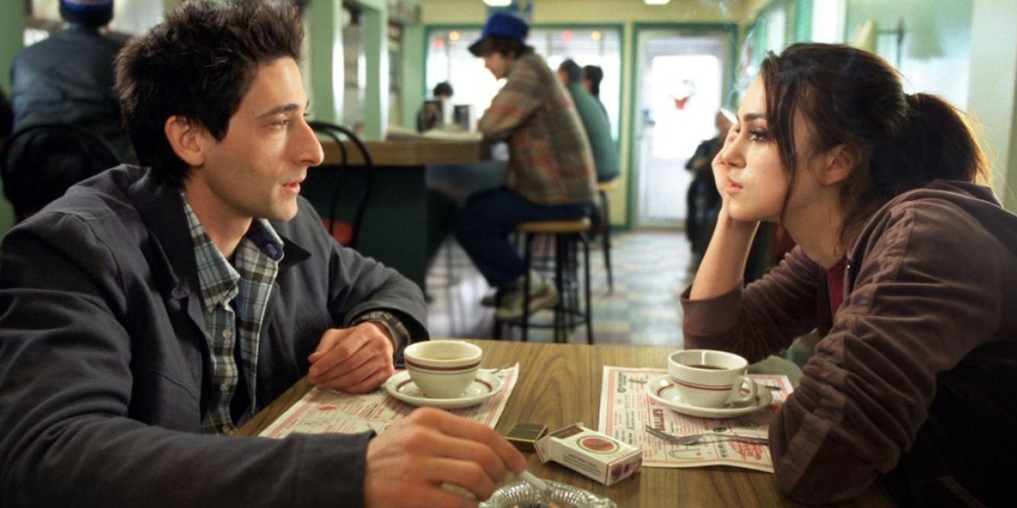 Adrien Brody and Keira Knightley sit across from each other at a small table in a diner in The Jacket.