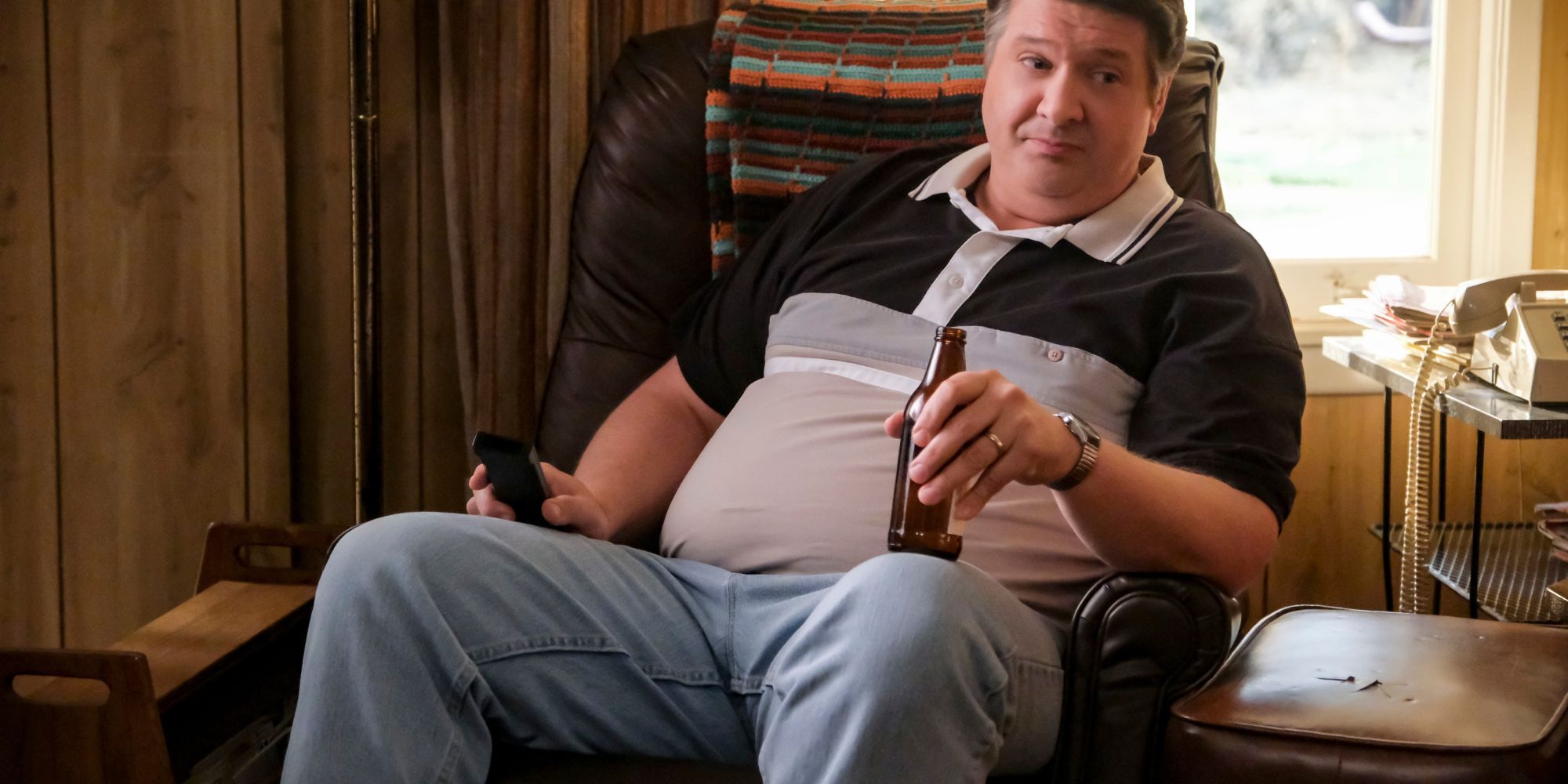 Lance Barber as George Sr. sitting in his recliner, holding a beer in Young Sheldon