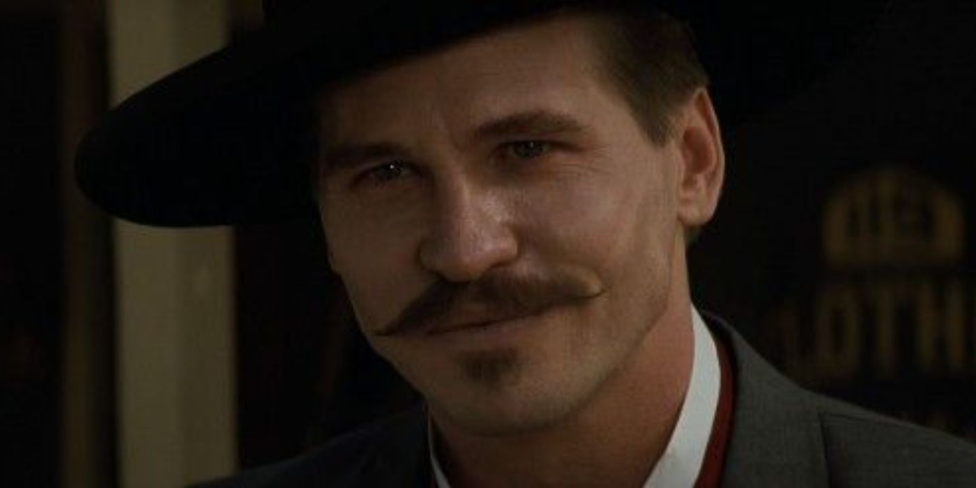 Val Kilmer comme Doc Holliday souriant à quelqu'un à Tombstone.