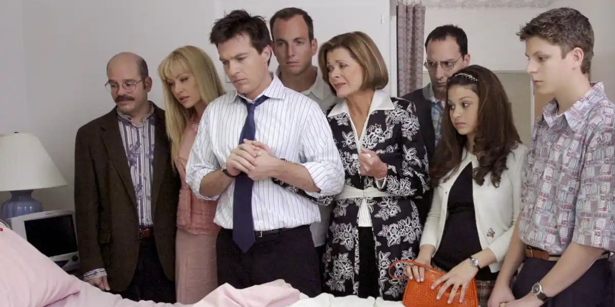 The cast of Arrested Development looking in the same direction while at a hospital room.