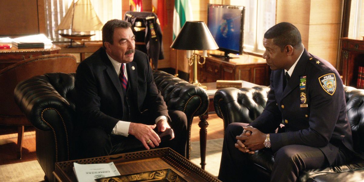 A man in a suit talking to a man in a police uniform in an office.