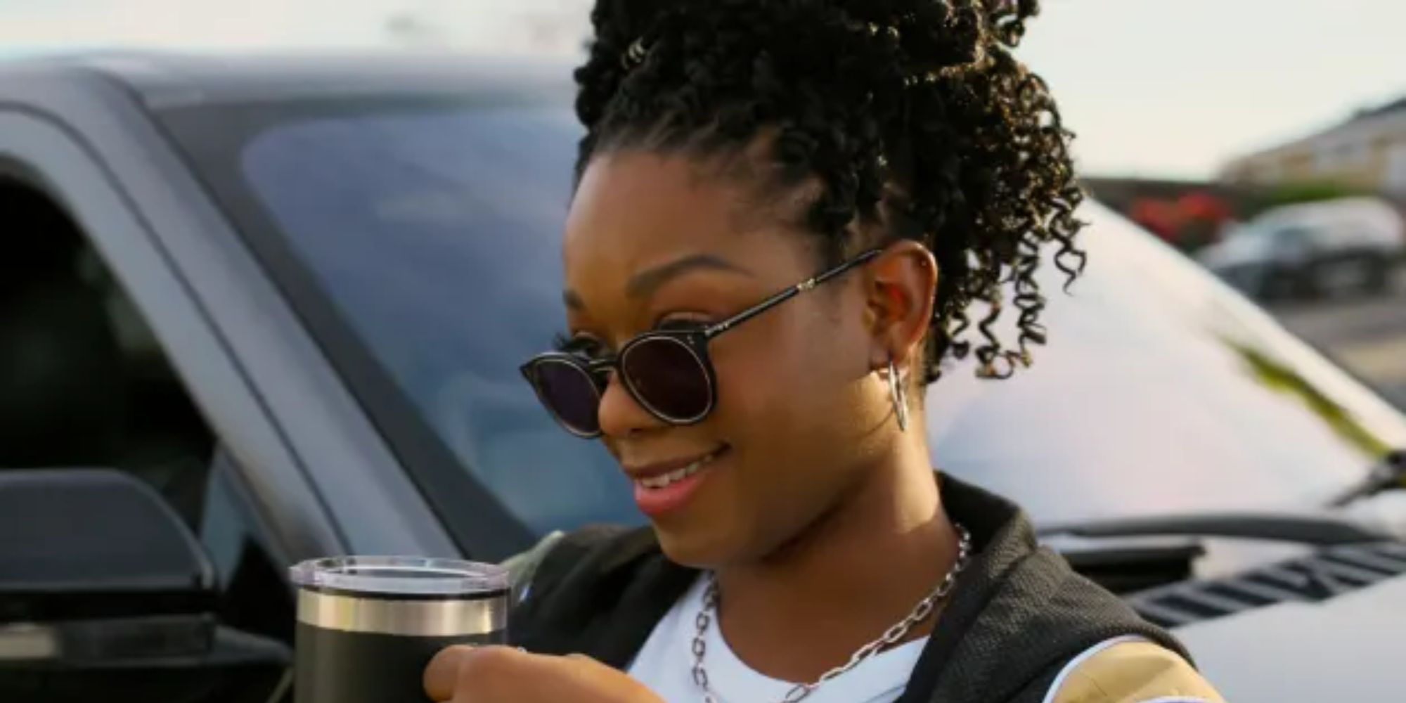 Izzy Lets holding a thermos outside in near a car in The Lincoln Lawyer