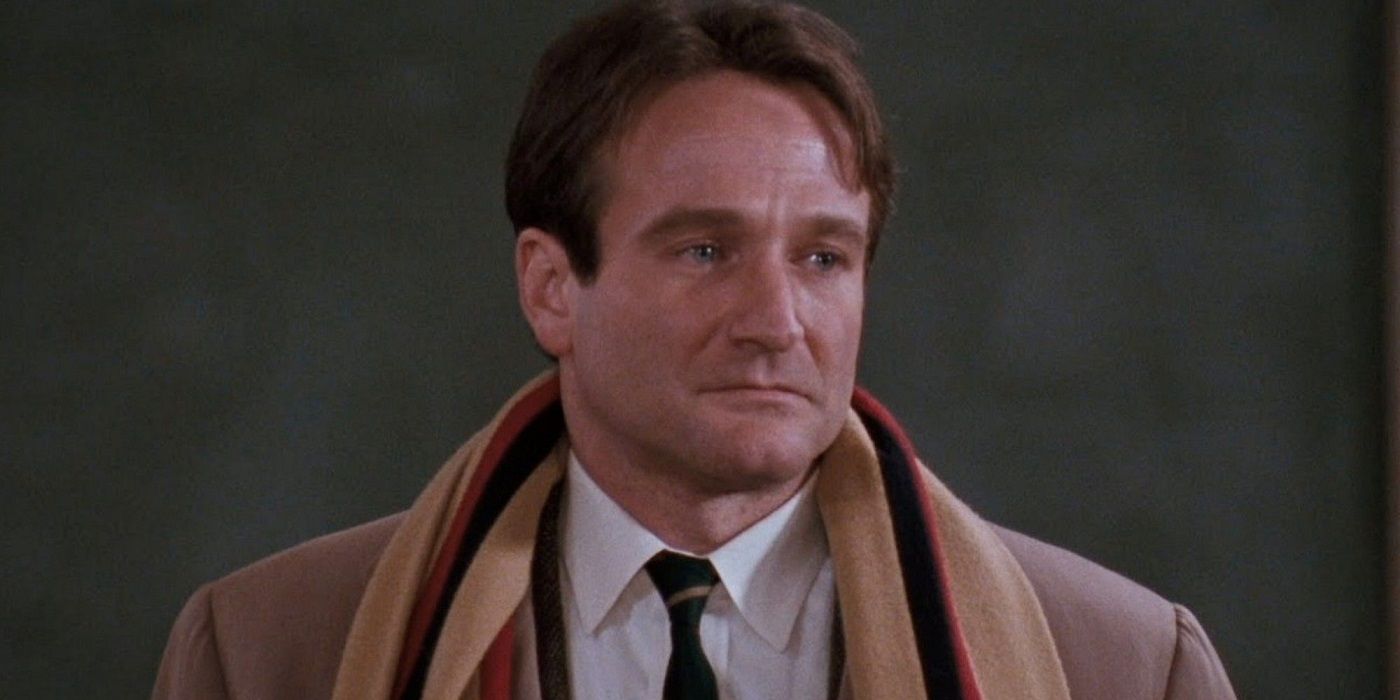 John Keating (Robin Williams) looking slightly right with a sad expression while wearing a brown coat and multi-colored scarf in Dead Poets Society
