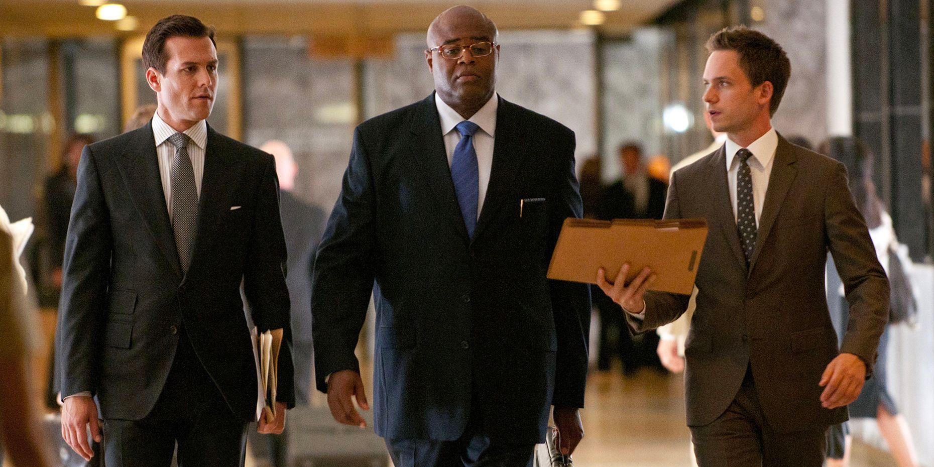 Gabriel Macht, Chi McBride and Patrick J. Adams, as Harvey, Tereence, and Mike walking down a hall in Suits. 