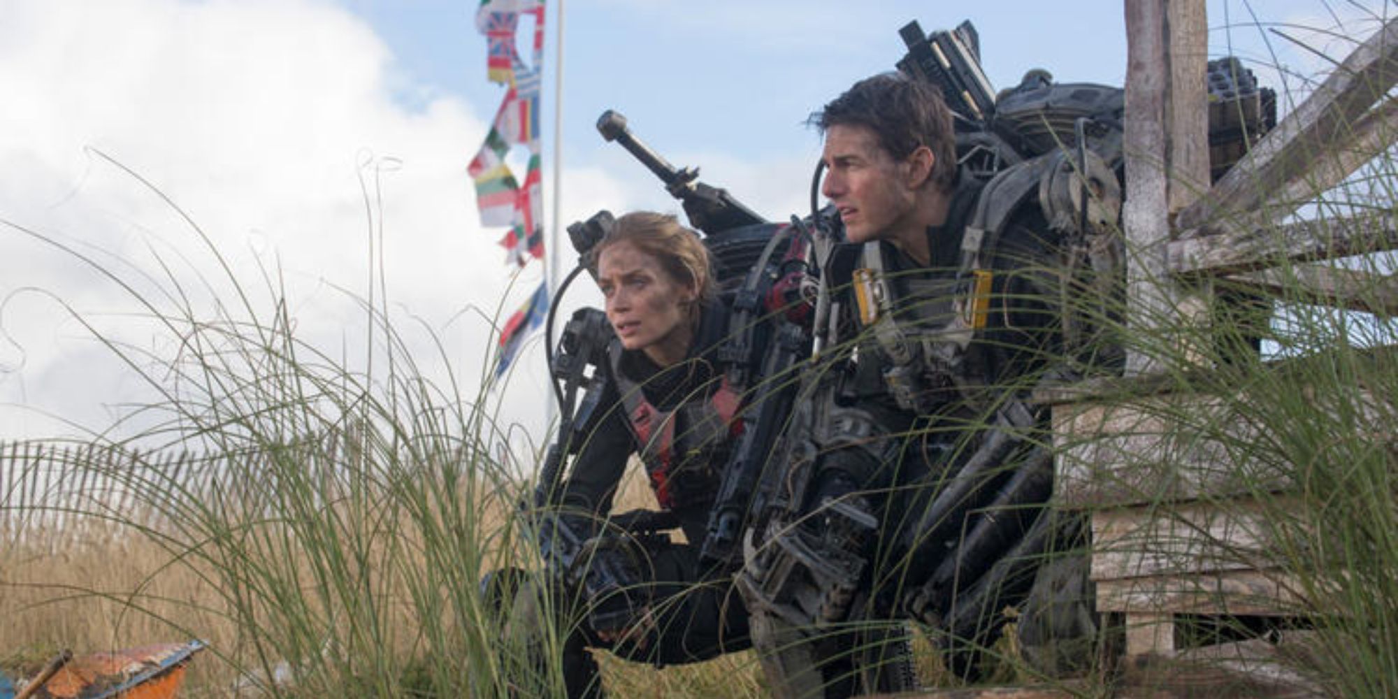 Rita y William se arrodillan y miran hacia adelante con sus trajes mecánicos en la película All You Need Is Kill.