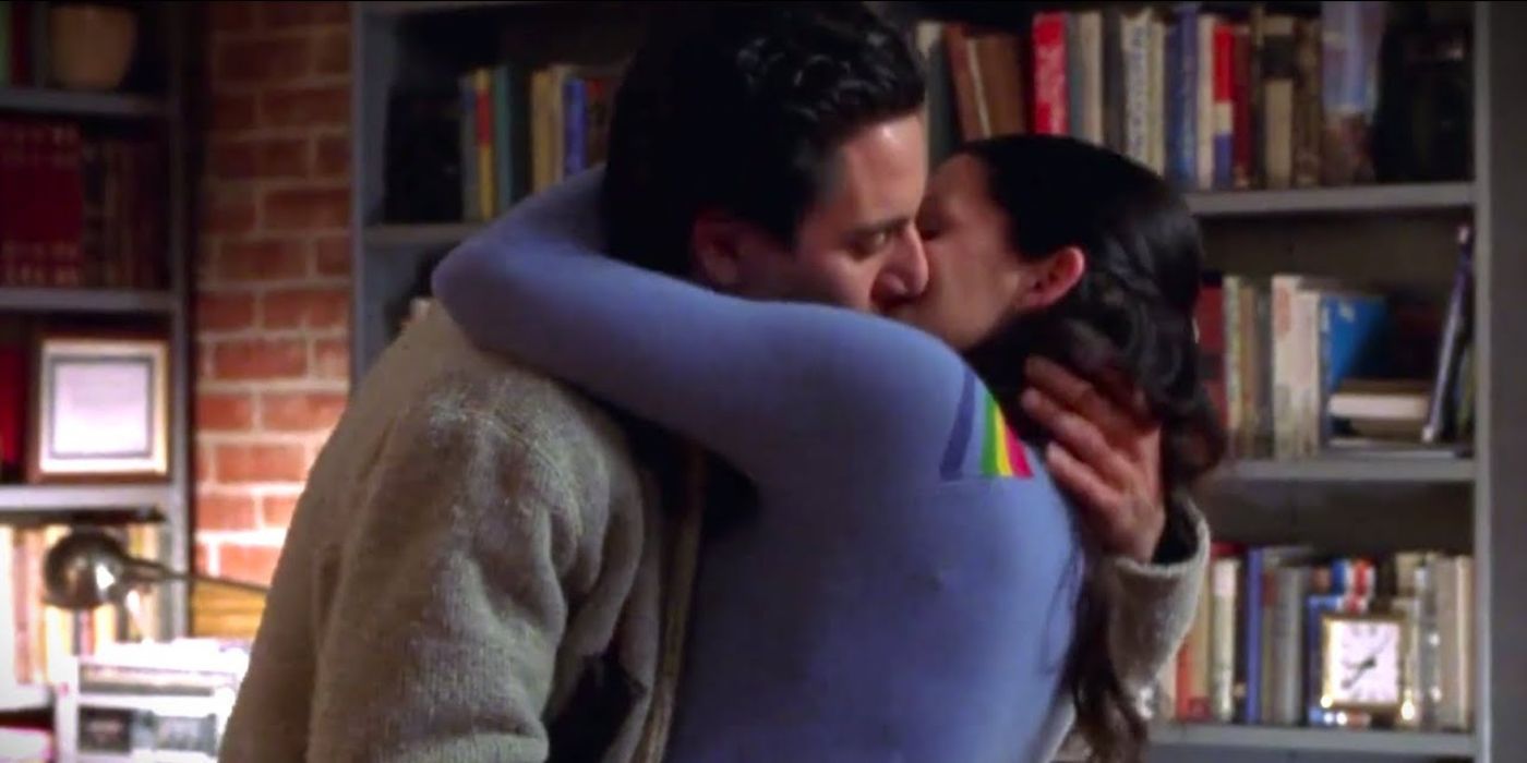 Lorelai (Lauren Graham) and Max Medina (Scott Cohen) kissing in front of a bookshelf in Max's apartment in Gilmore Girls Season 1