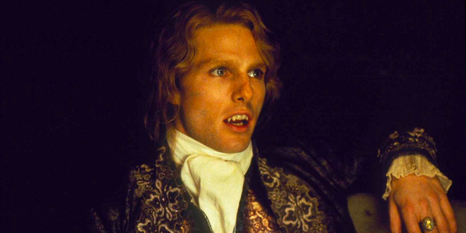 Lestat de Lioncourt, a centuries old vampire, sits in a darkened room in adorned in fancy 18th century attire.