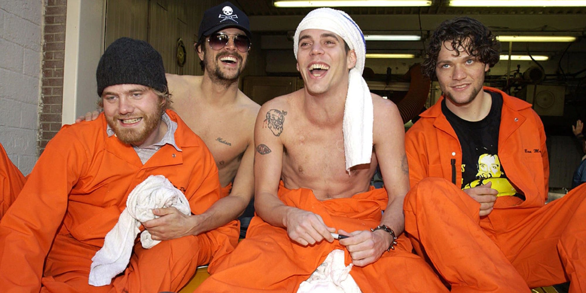 Steve-O, Johnny Knoxville, and cast laughing and wearing orange jumpsuits on Jackass