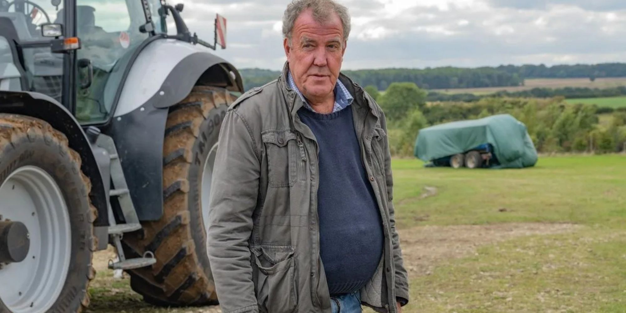 Jeremy Clarkson from Clarkson's Farm standing beside a tractor.