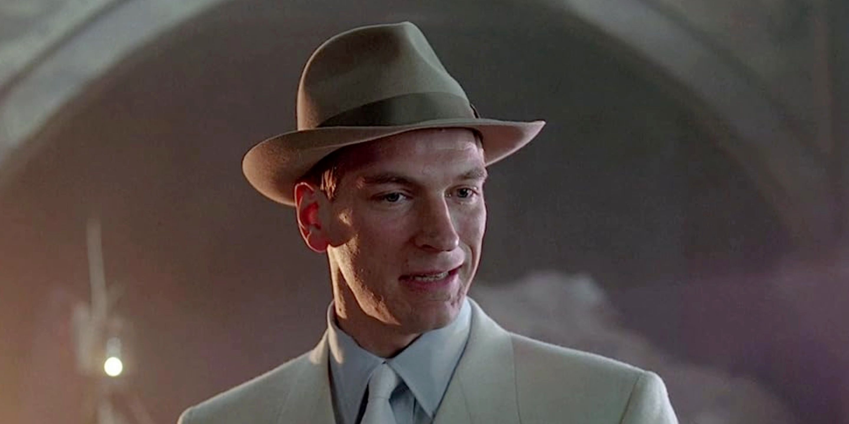 close-up of Julian Sands in 'Naked Lunch' (1991) wearing a suit and fedora