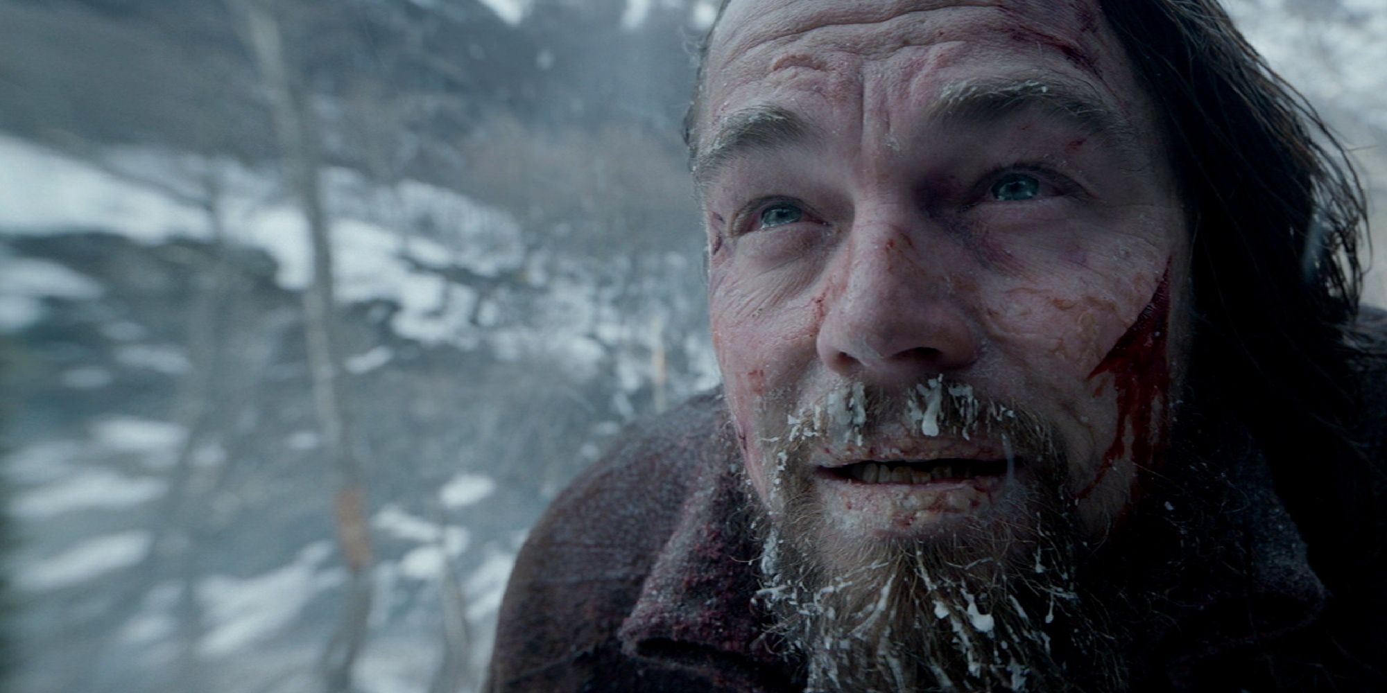 A close-up of Hugh Glass with wounds on his face and snow hitting in 'The Revenant'