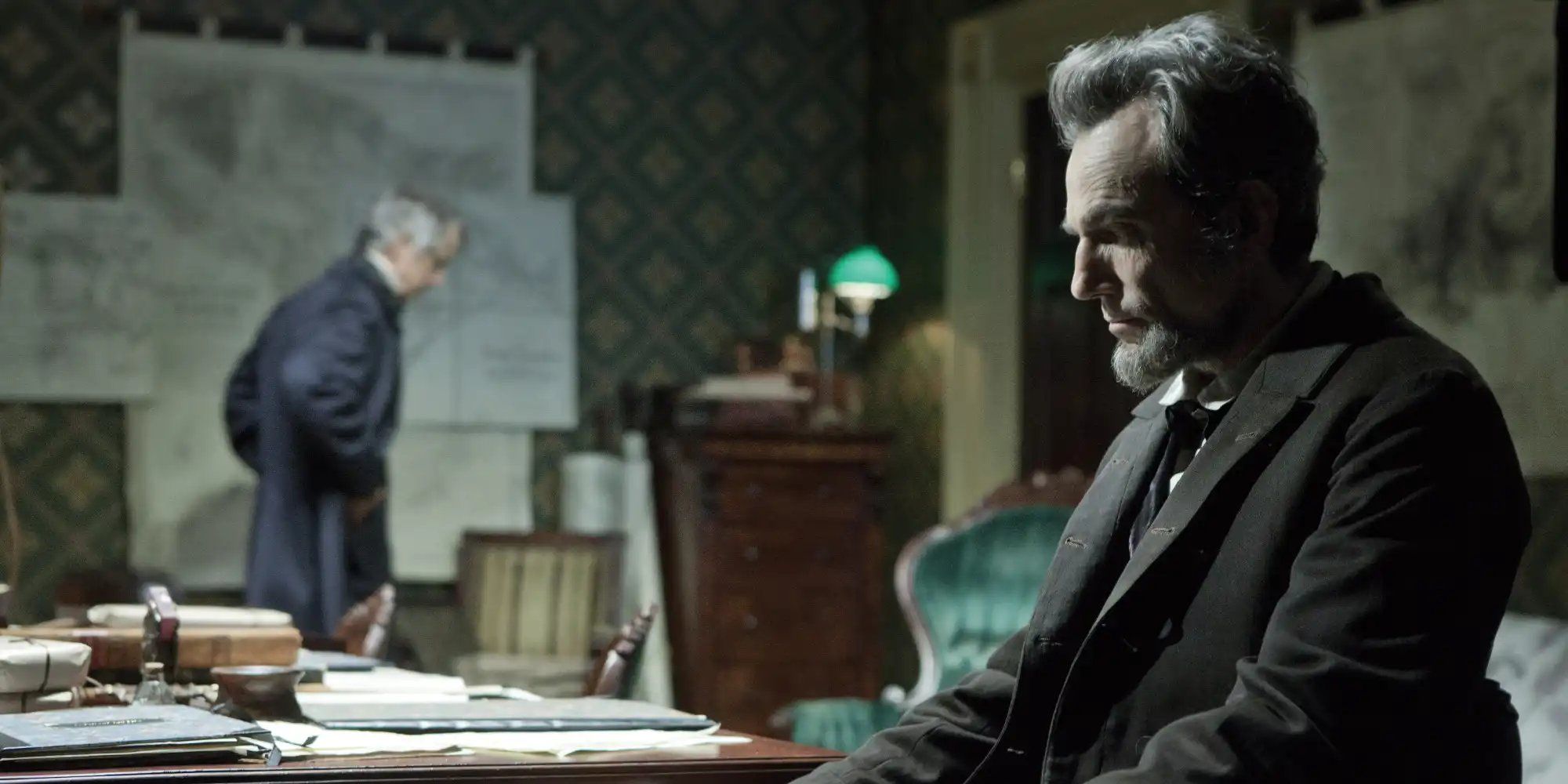 American President Abraham Lincoln (Daniel Day-Lewis) sits behind his desk.
