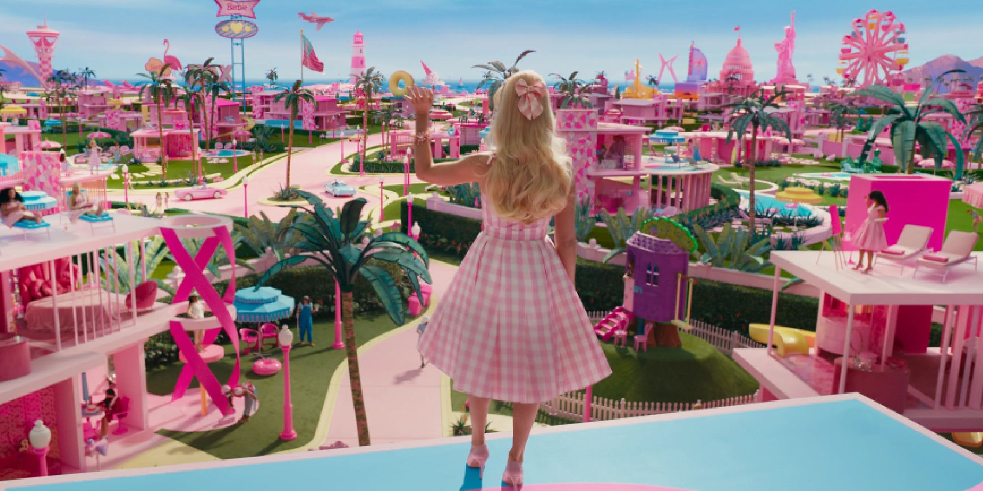 Margot Robbie as Barbie waving at Barbie World in Barbie