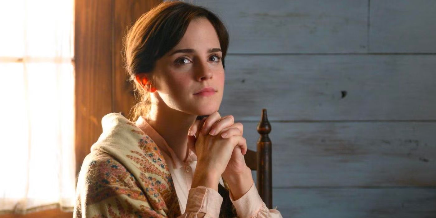 Meg March (Emma Watson) clasps her hands in prayer as she sits by a window in her house. 