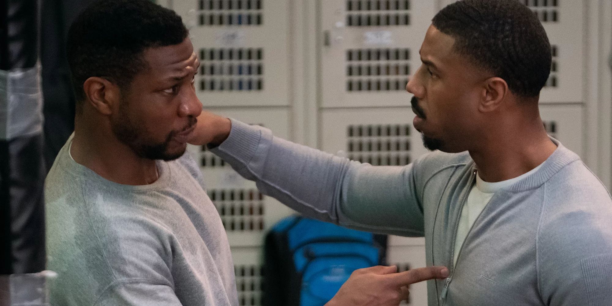 Michael B Jordan and Jonathan Majors as Adonis "Donnie" Creed and Damian Anderson, talking in a locker room in Creed III