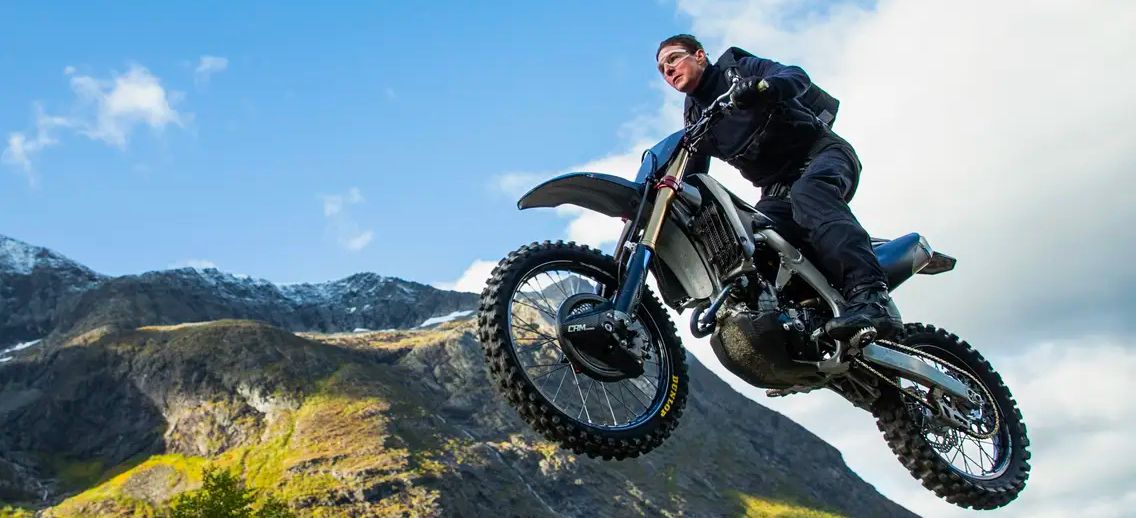 Ethan Hunt (Tom Cruise) jumps off a cliff on his motorcycle.