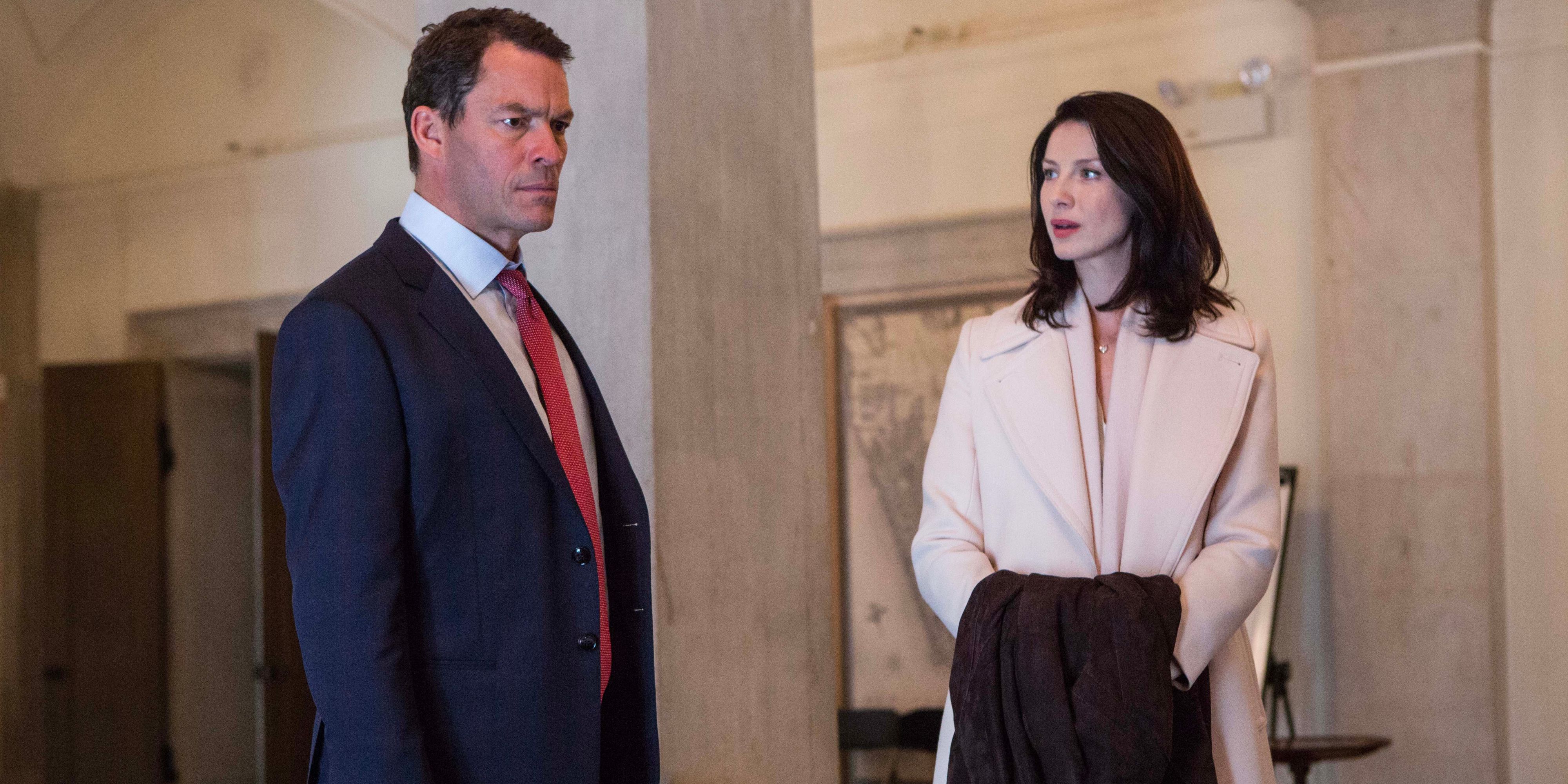 A greedy business CEO scowls as he thinks while his chief communications officer stands by him, her hands folded under a coat.