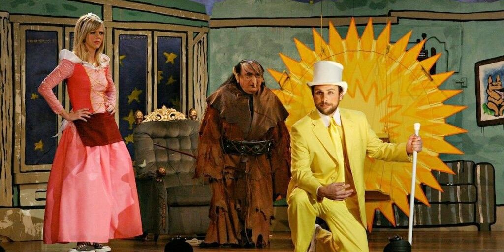 Still from "It's Always Sunny in Philadelphia": Dee (Kaitlin Olson), Frank (Danny DeVito) and Charlie (Charlie Kelly) are on stage dressed in ridiculous costumes for The Nightman Cometh.