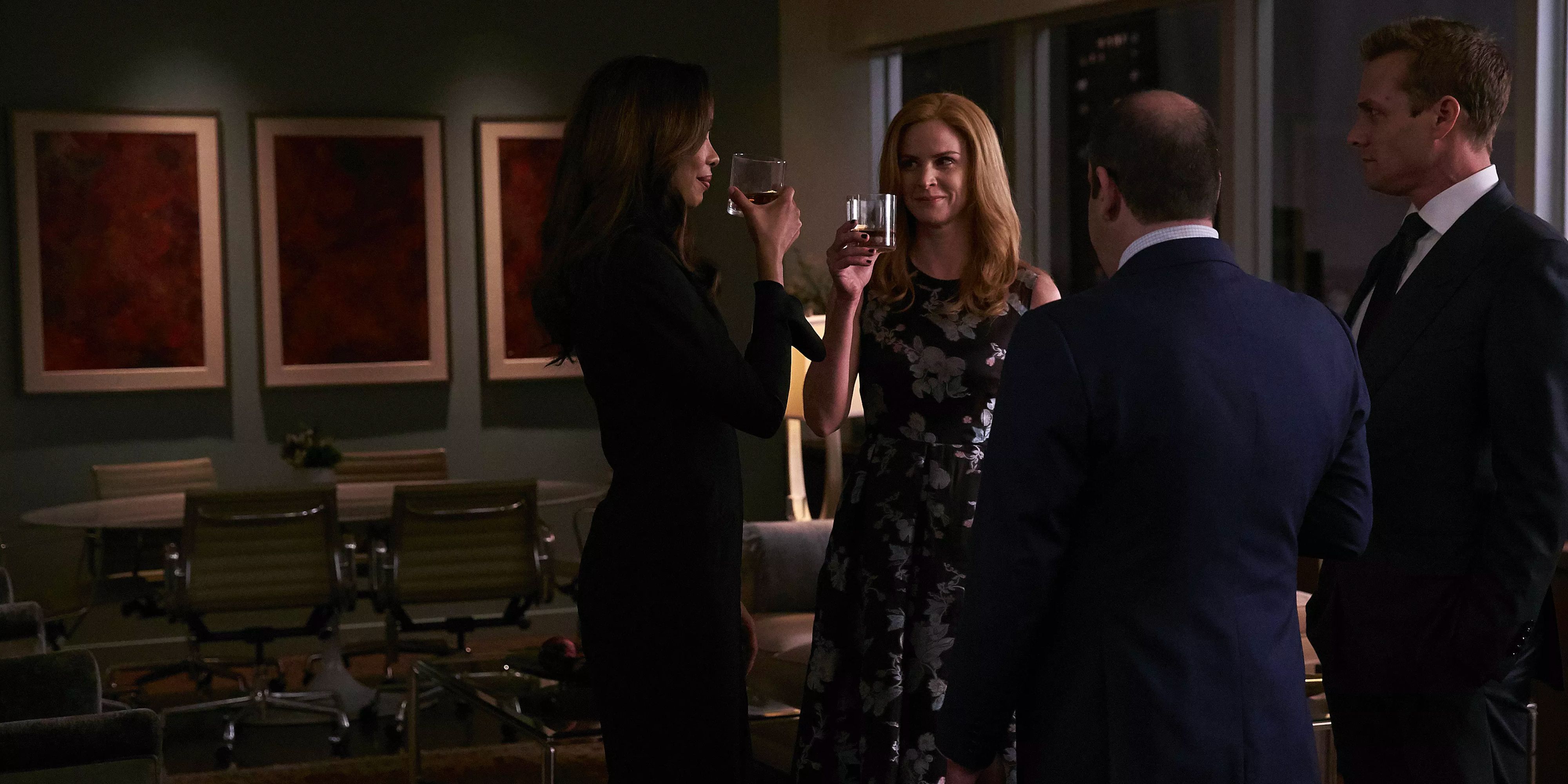 Jessica, Donna, Louis, and Harvey raise a toast in the office at night.