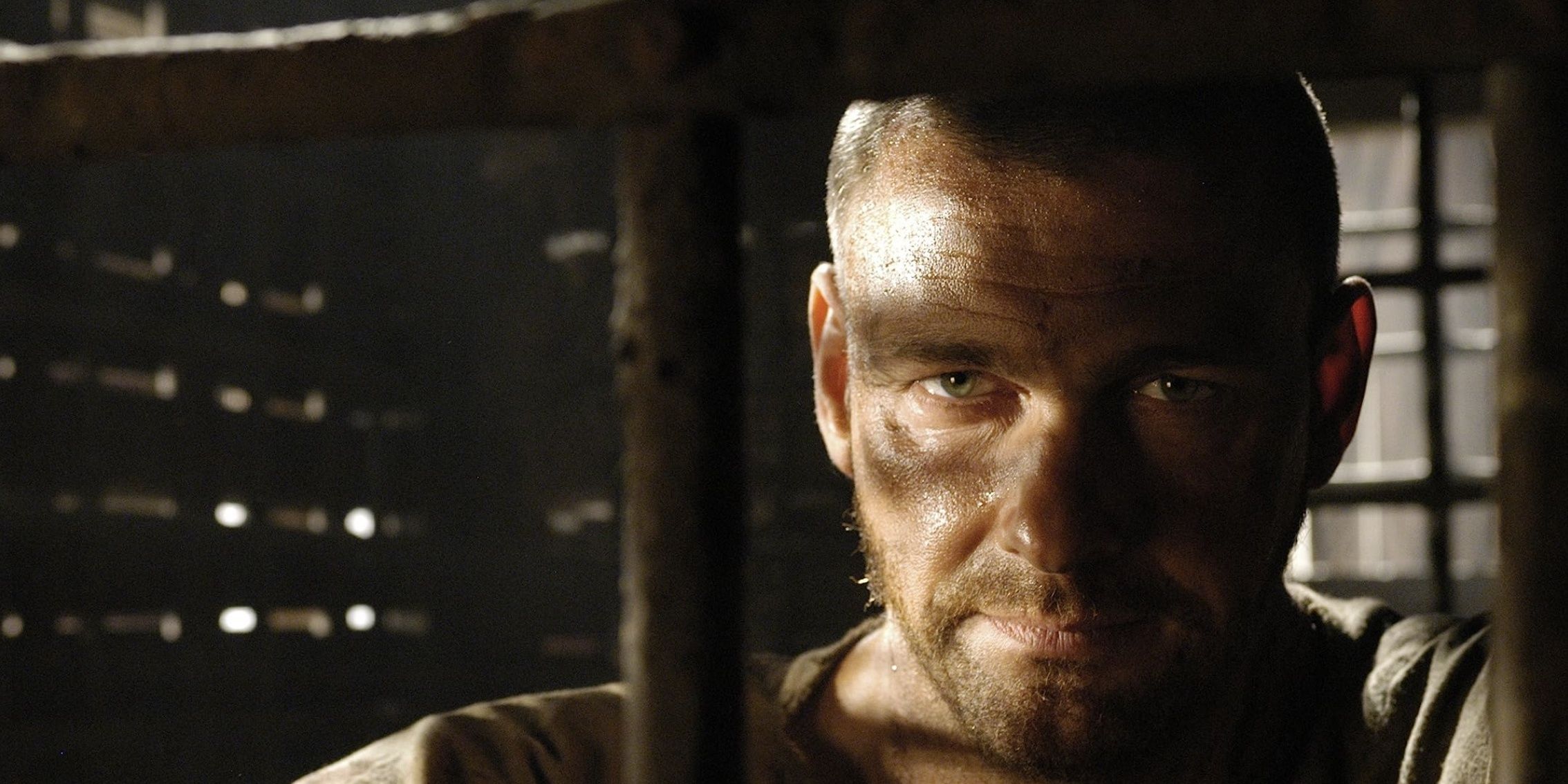 Ray Stevenson as Titus Pullo in a cage staring at a person offscreen in &lsquo;Rome&rsquo;