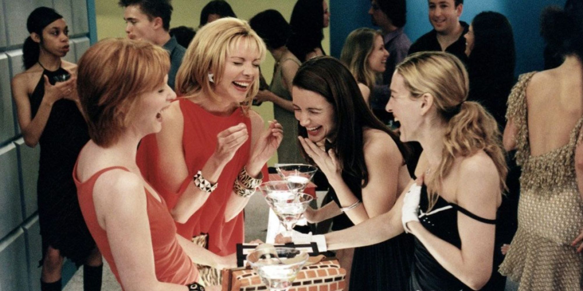 Miranda, Samantha, Charlotte, and Carrie laughing at a bar in Sex and the City