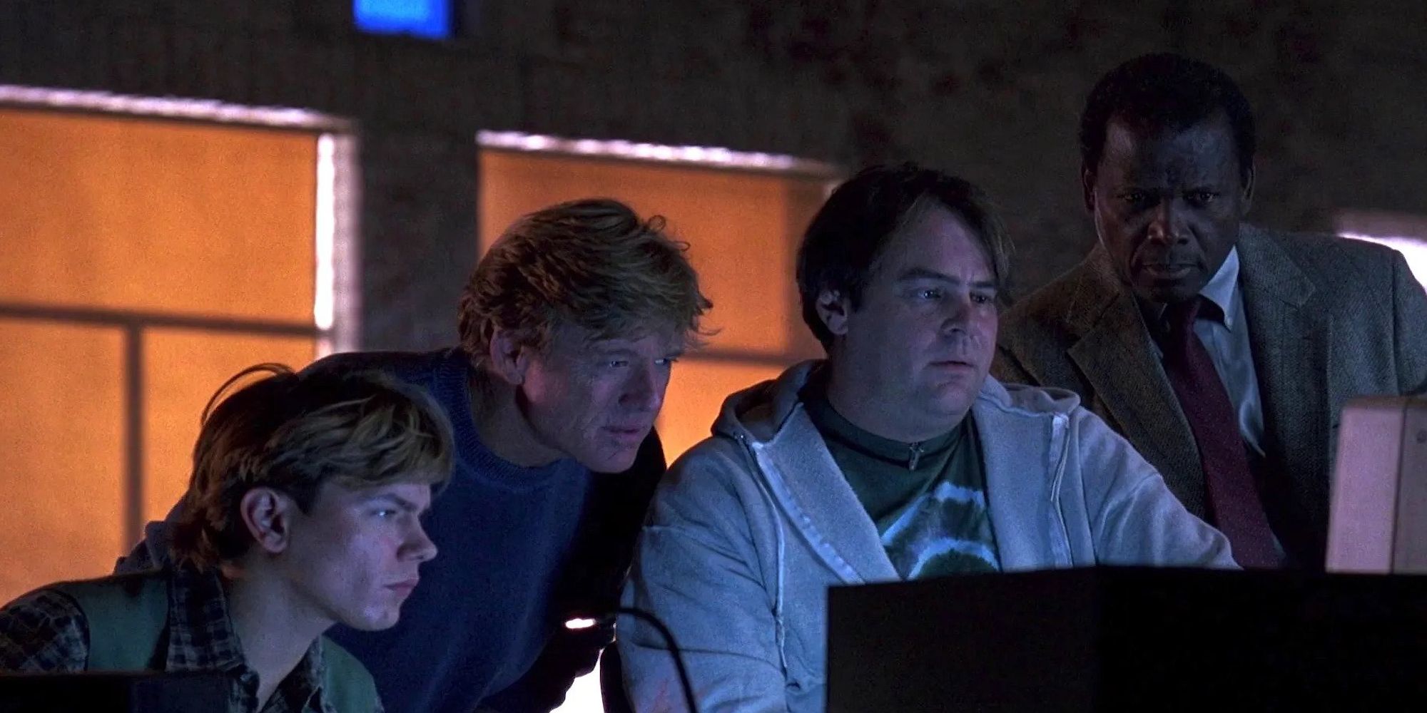 The main cast members of the movie Sneakers sitting around a computer screen