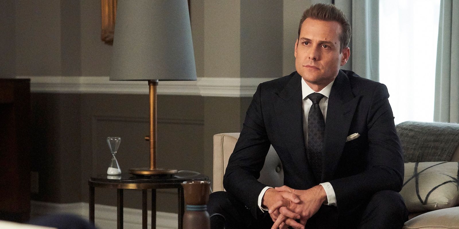 Harvey Specter (Gabriel Macht) sitting on a couch in one of the scenes in Suits.