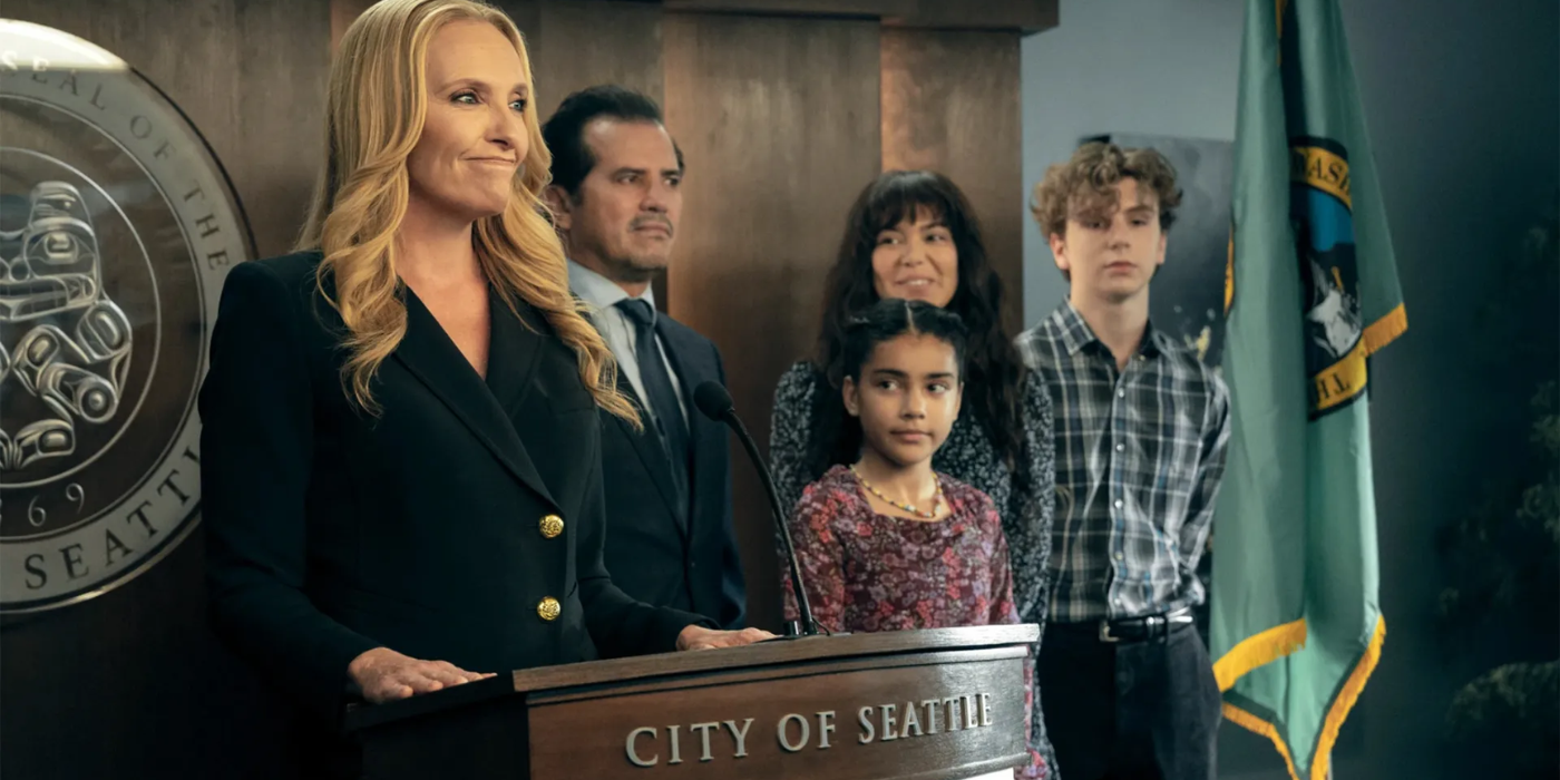 A woman stands behind a podium, several kids and a man beside her, in a scene from The Power.