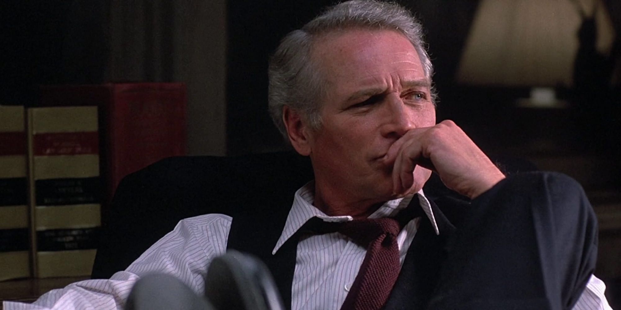Paul Newman as Frank Galvin sitting with his feet up on his desk and his left hand on his lips in the film The Verdict.