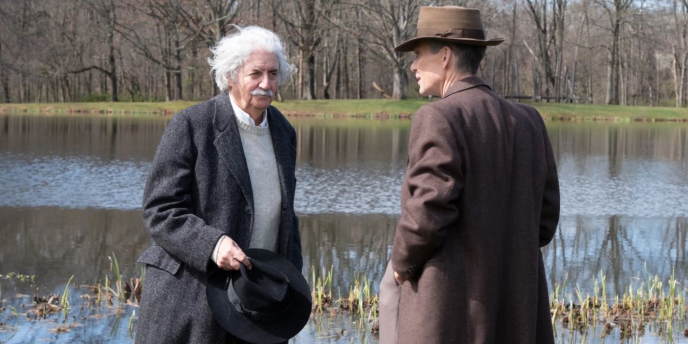 Tom Conti and Cillian Murphy as Albert Einstein and J. Robert Oppenheimer, standing by a pond and talking in Oppenheimer 