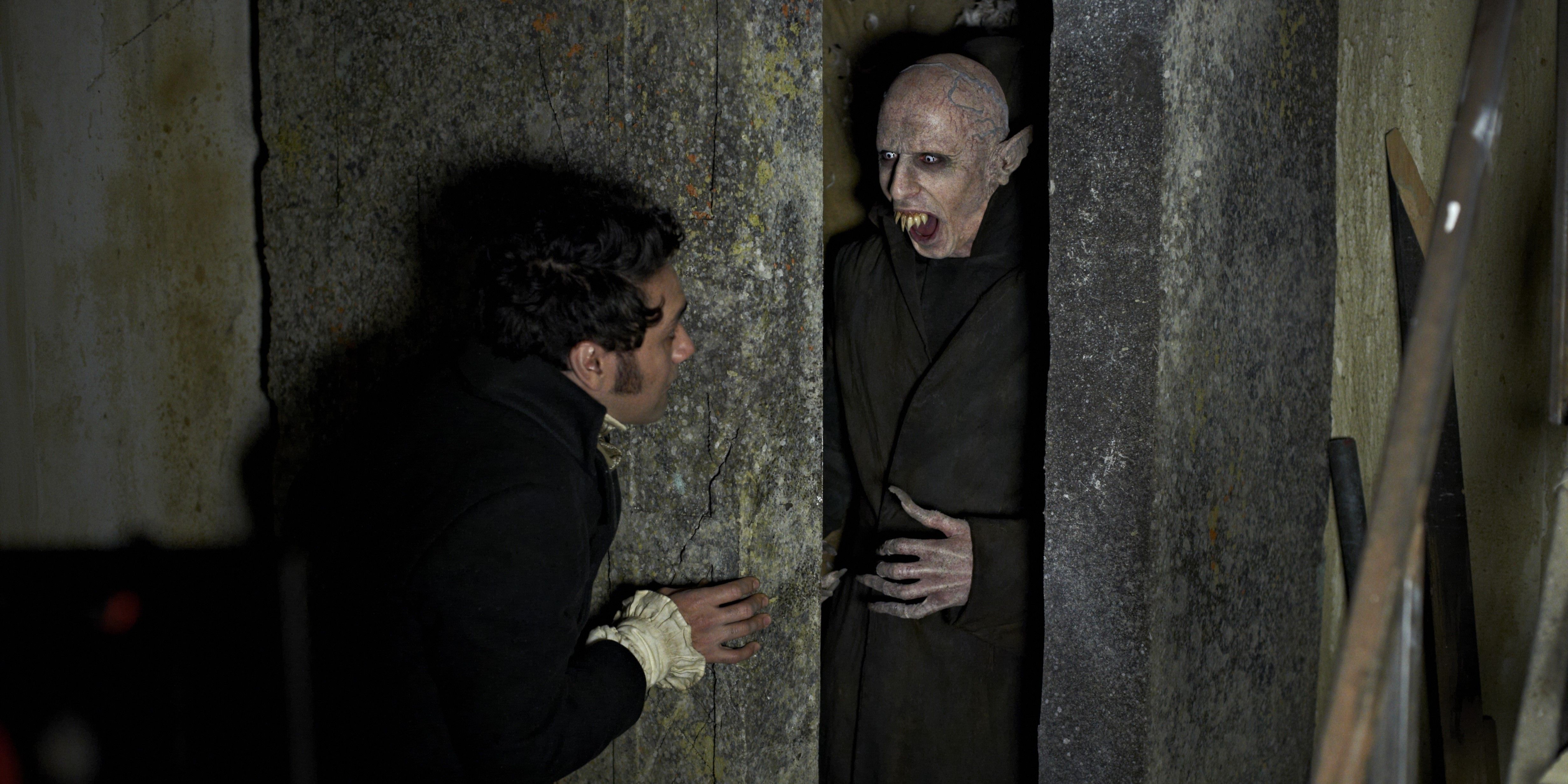 Image from 'What We Do in the Shadows' of Taika Waititi looking at a Nosferatu-inspired vampire character in a stone crypt.