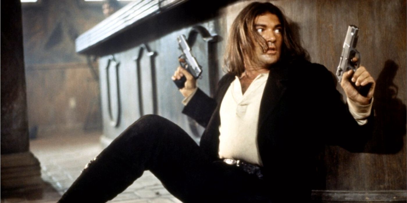 Antonio Banderas as El Mariachi hiding behind a bar with two guns drawn in Desperado