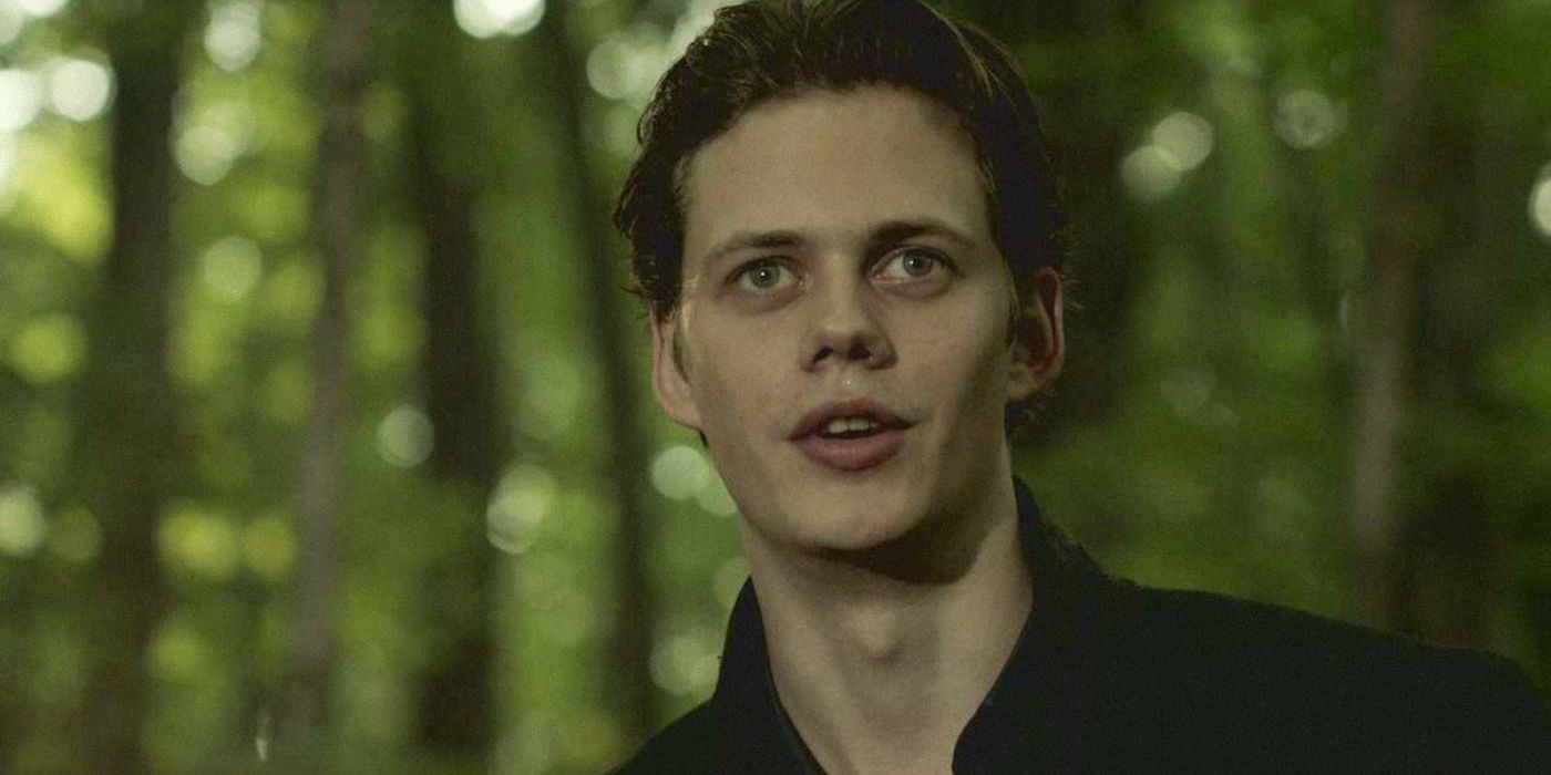 Roman Godfrey in the forest smiling and looking ahead in Hemlock Grove