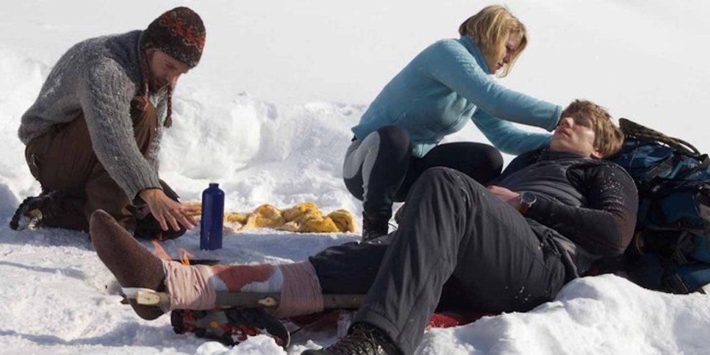 A man and a woman comfort an injured man in Devil's Pass