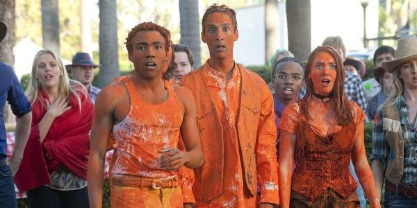 Still from 'Community': Annie, Troy and Abed are all covered in orange paint, looking shocked.