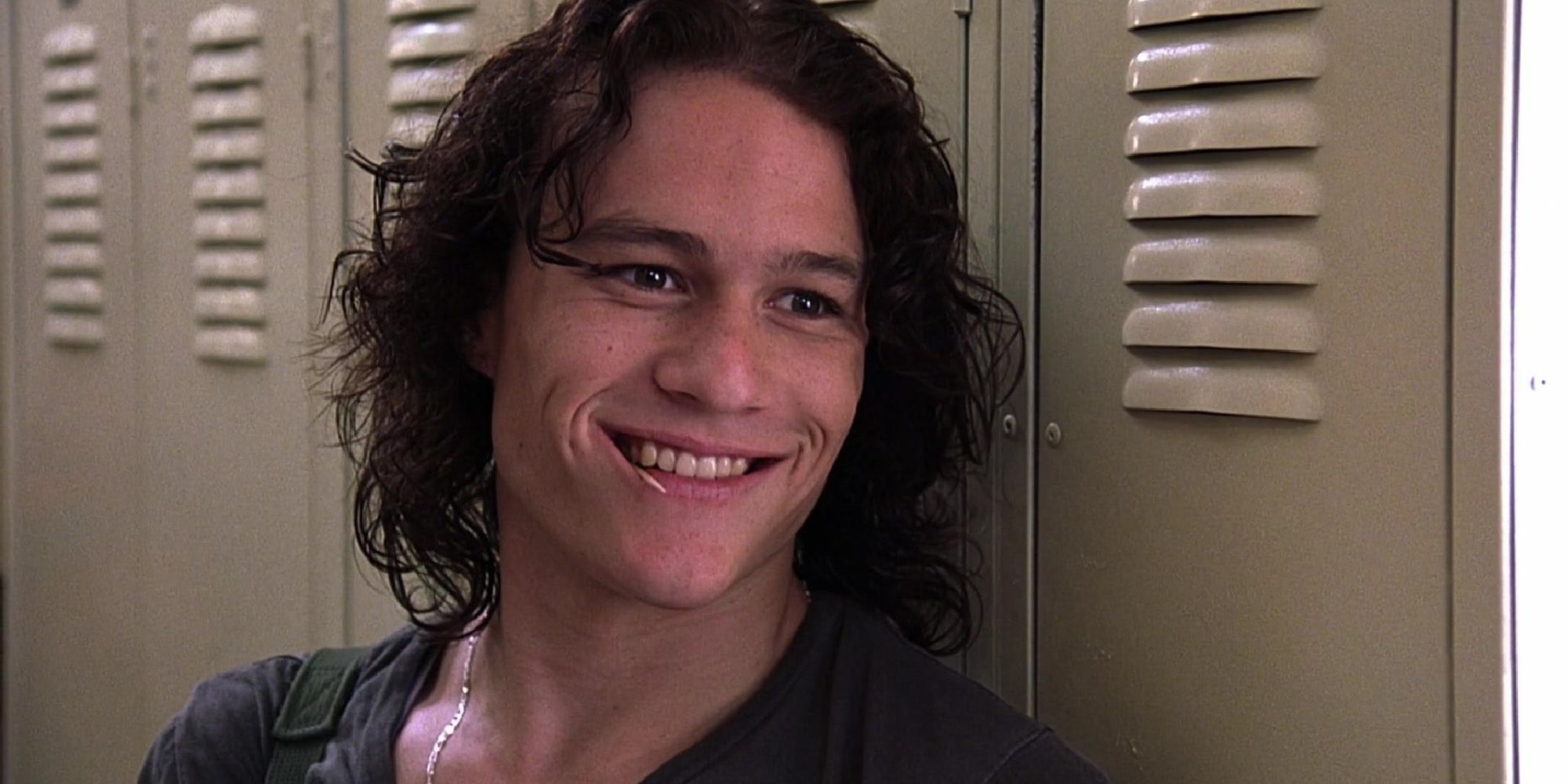 Heath Ledger as Patrick Verona, smiling beside a row of lockers in 10 Things I Hate About You