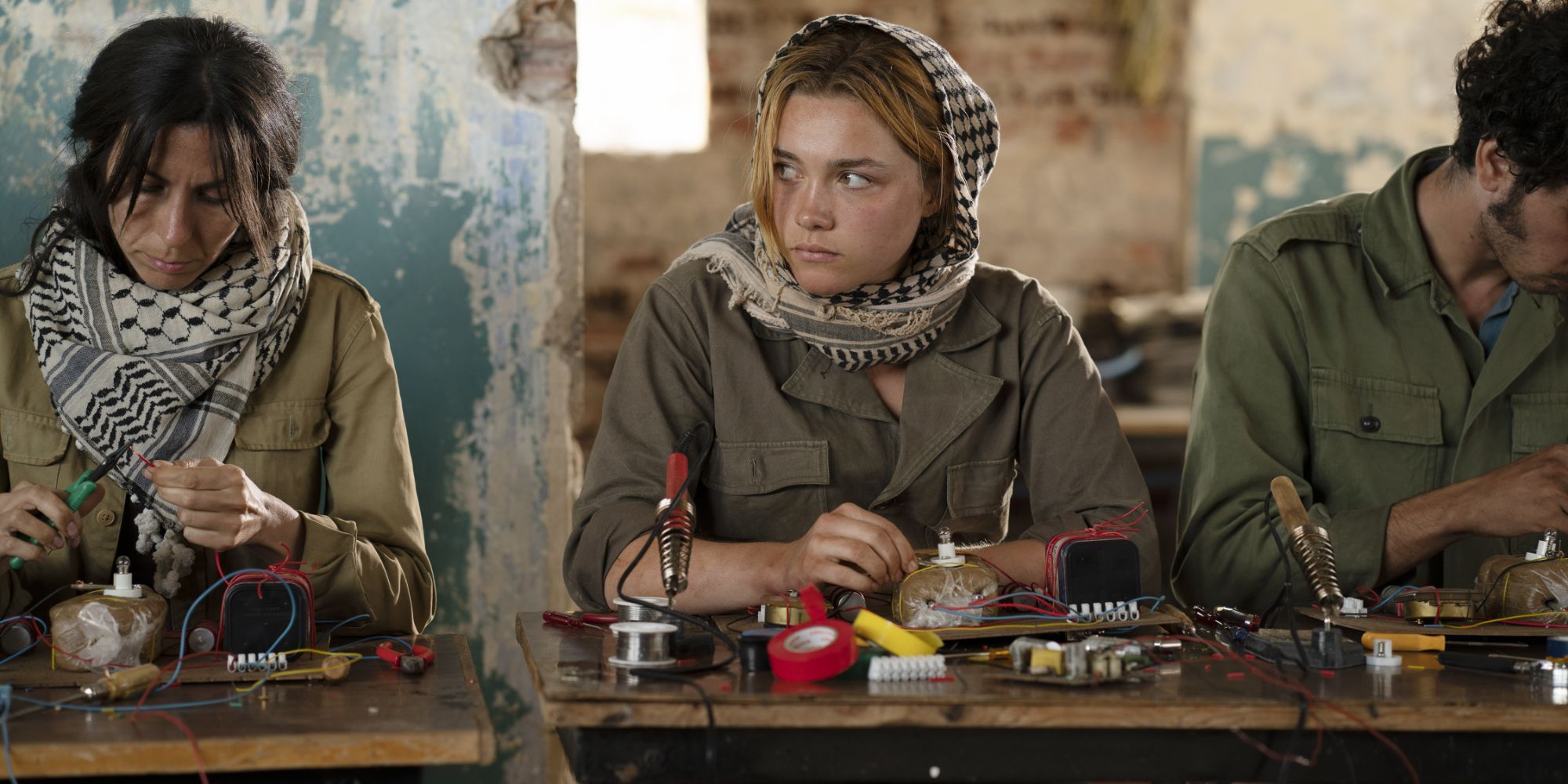 Florence Pugh wears a headscarf and looks tense wiring explosives in a factory in The Little Drummer Girl.