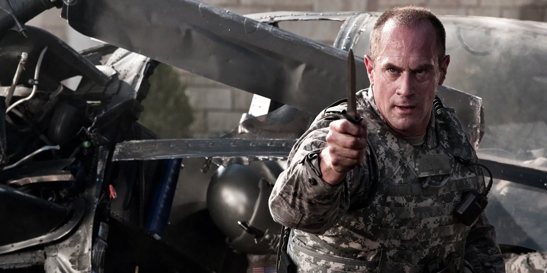 An army Colonel wields a knife as he emerges from a crashed helicopter and faces off with a power alien tyrant.