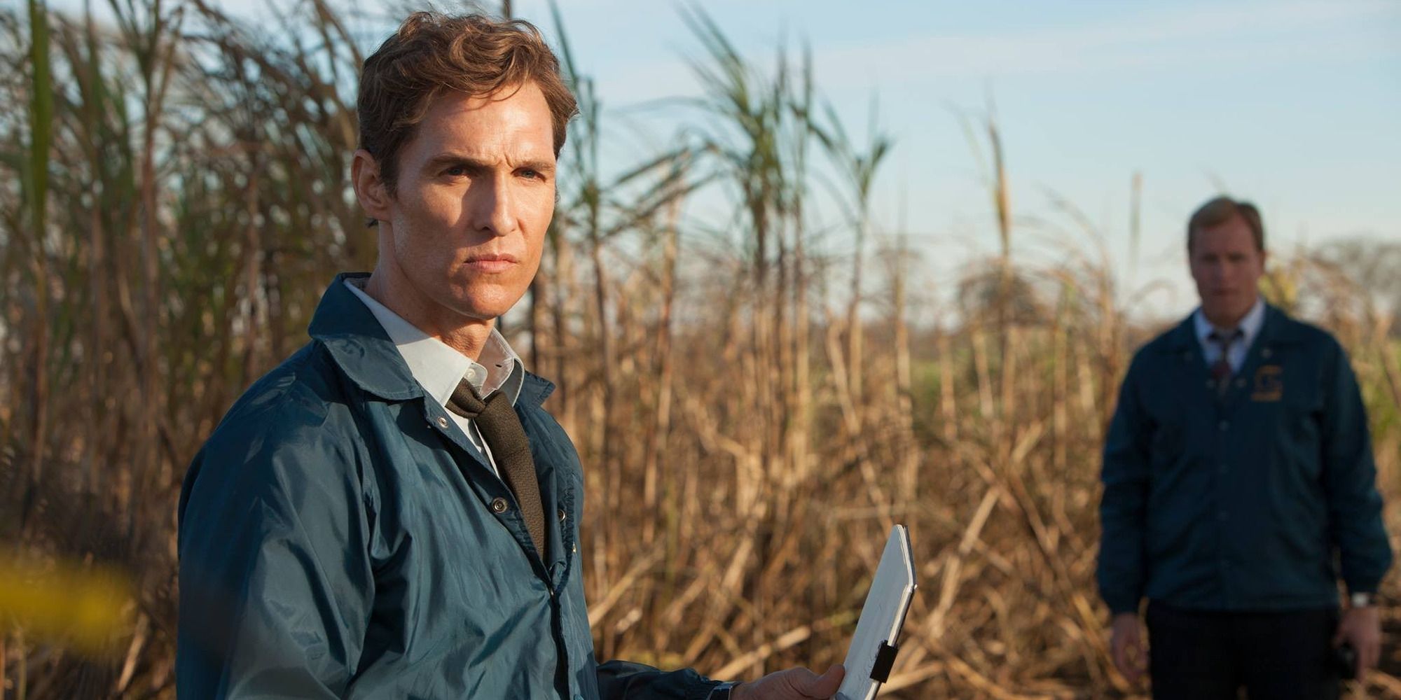 Cohle and Hart standing in a cornfield with a notepad