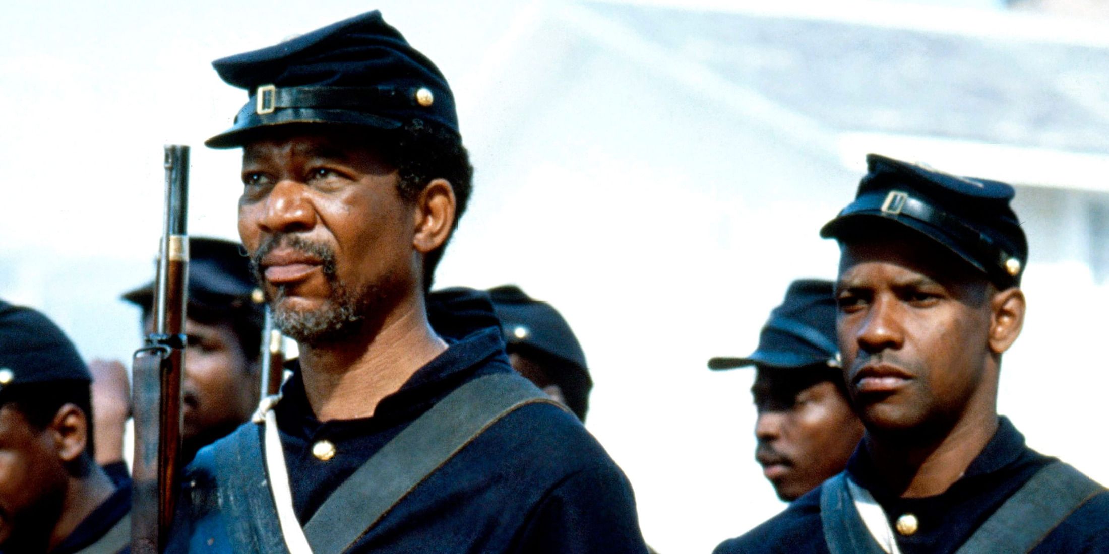 two Black soldiers standing, looking serious, with guns