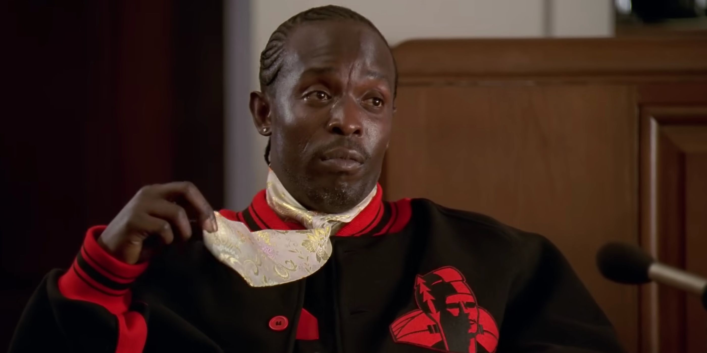 Omar Liddle (Michael K. Williams) testifies in court while wearing a black and red jacket and a floral tie.