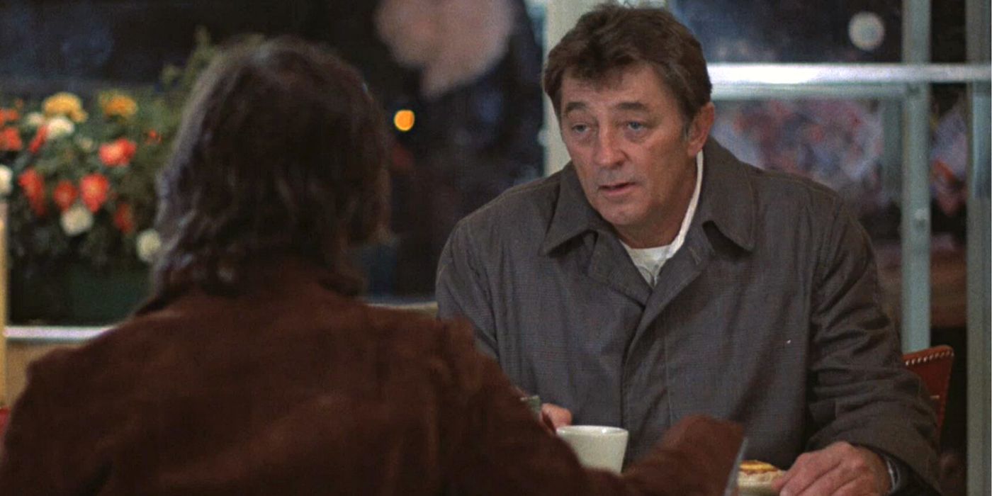 Robert Mitchum sentado em uma mesa em frente a alguém em Os Amigos de Eddie Coyle