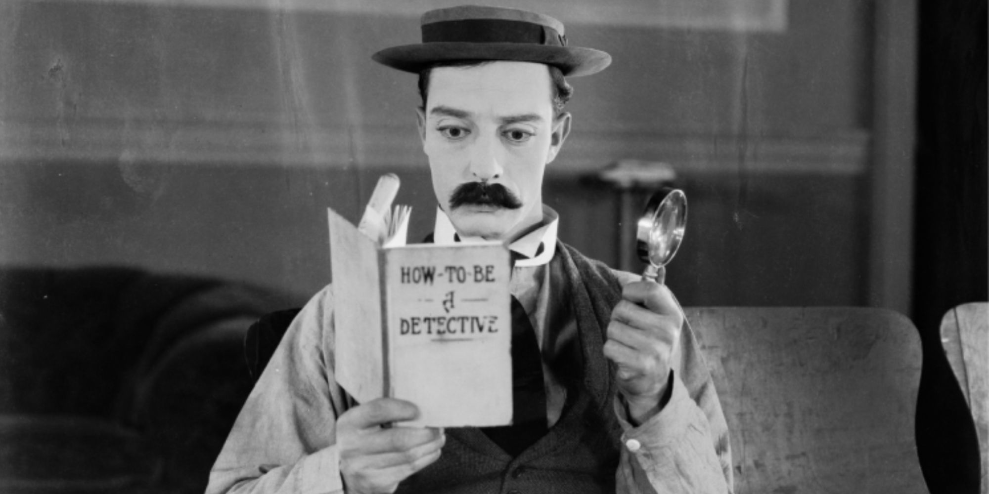 Buster Keaton as Sherlock Jr. reading a book in Sherlock, Jr.