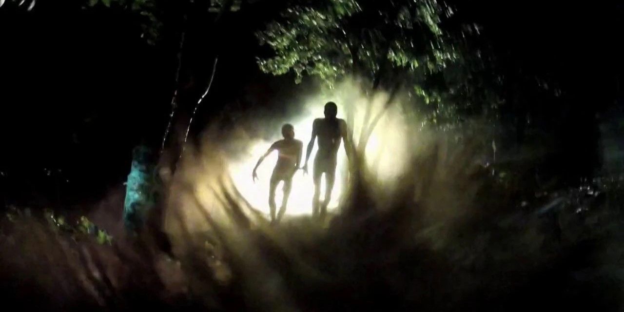 Still from VHS 2, 'Slumber Party Alien Abduction': two alien figures stand in a dark forest.