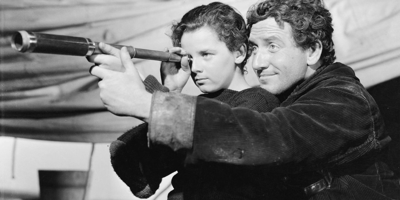A black and white shot of Spencer Tracy holding the binoculars of a child in Captains Courageous.