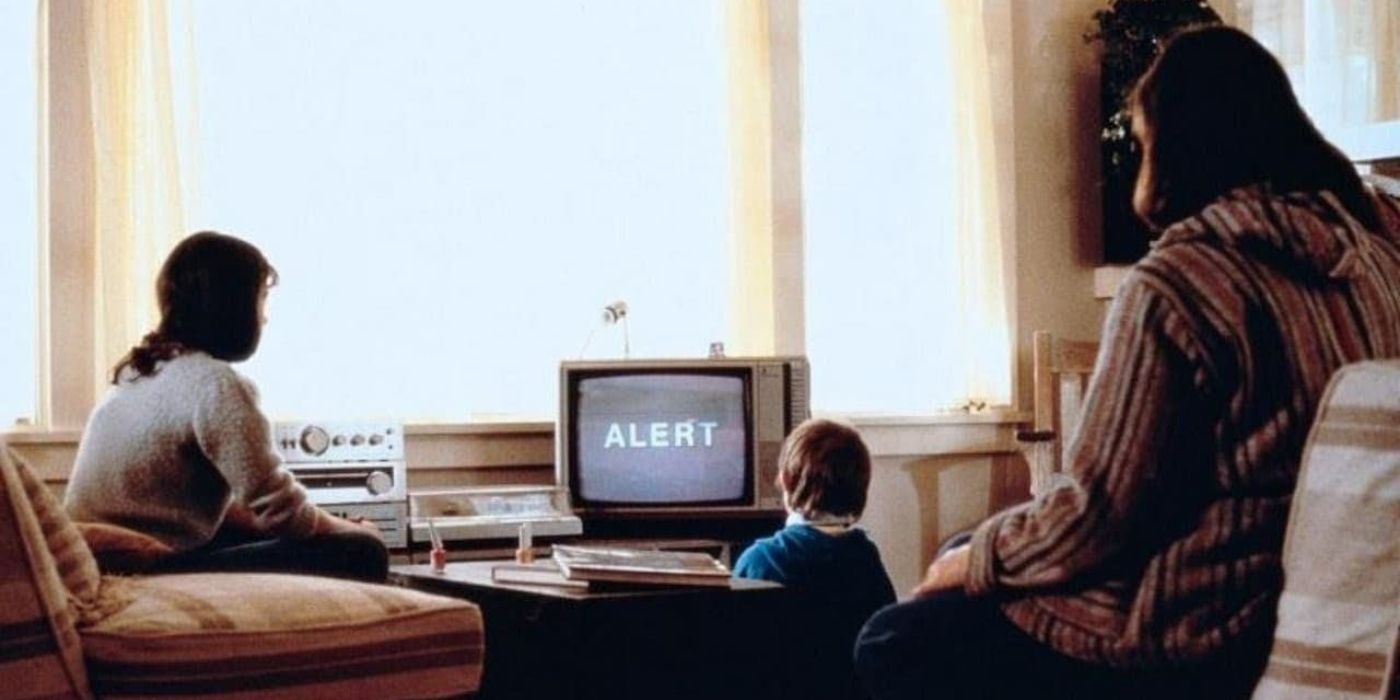 A woman and two children watch an alert on TV while a nuclear blast can be seen out the windows in 'Testament.'