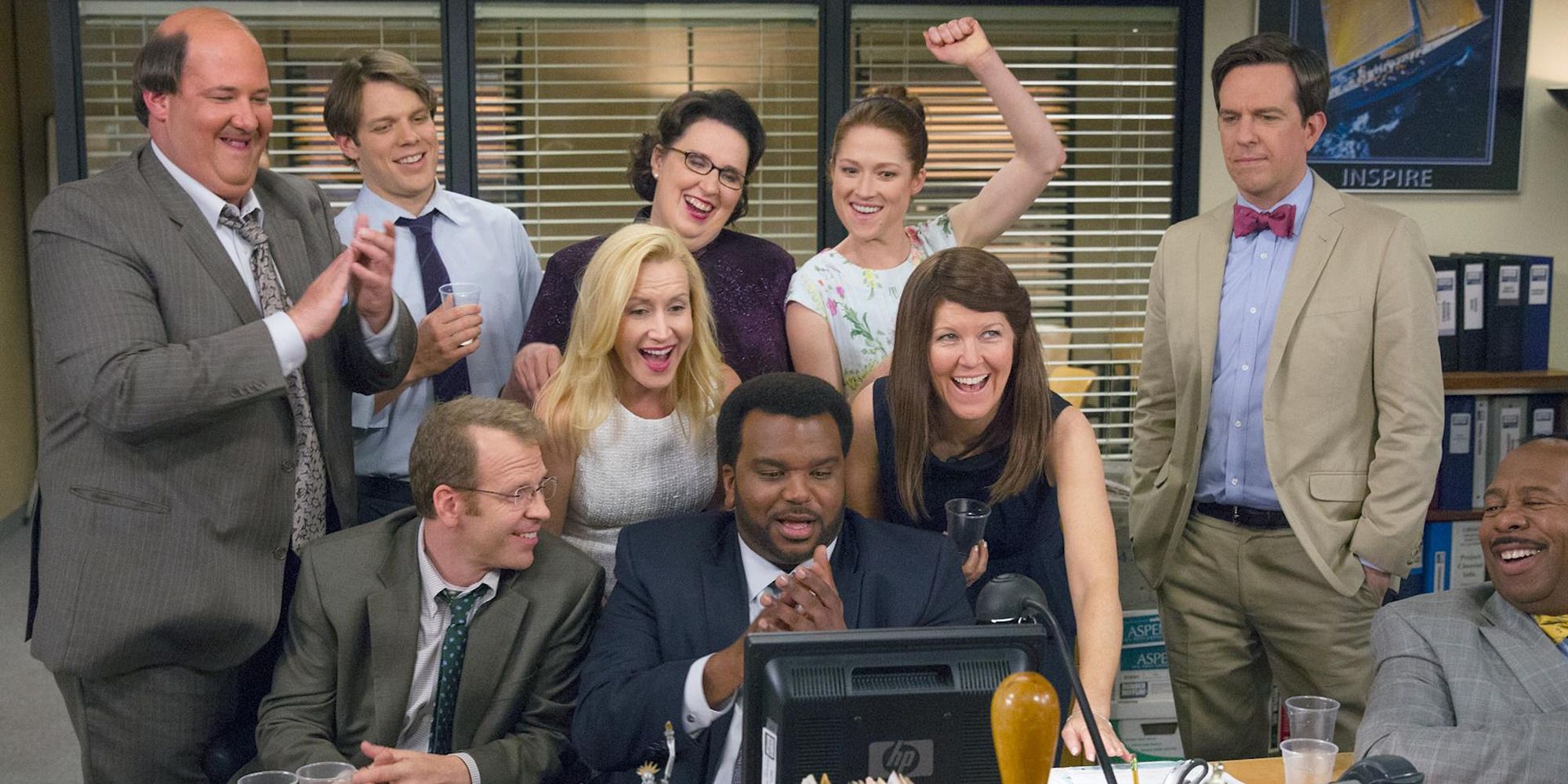 The cast of 'The Office' in front of a computer, cheering