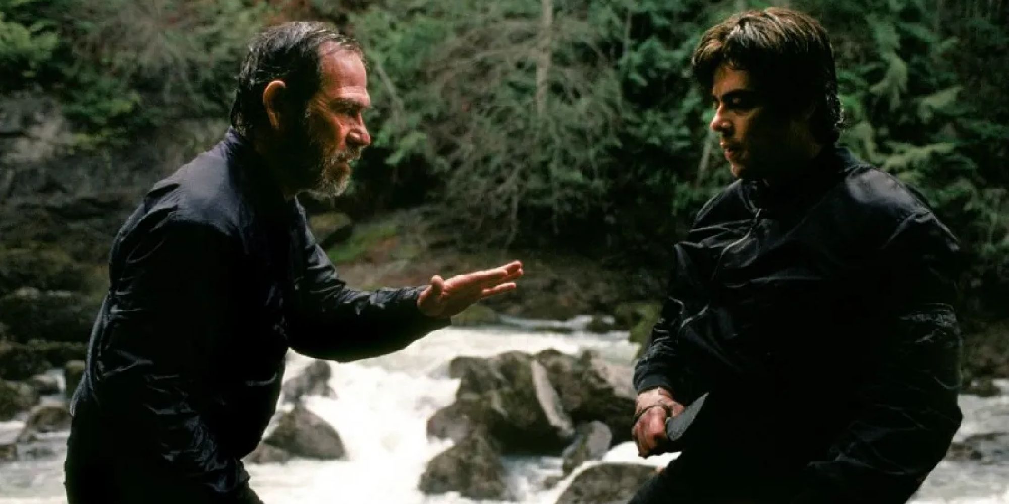Tommy Lee Jones and Benicio Del Toro as L.T. Bonham and Aaron Hallam arguing next to a waterfall in The Hunted.
