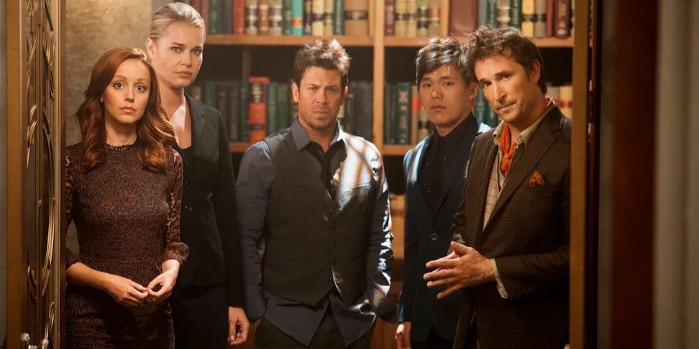The cast of 'The Librarians' standing in front of a bookcase.
