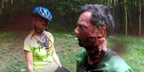 Two zombies, one in a bicycle helmet stand in a forest in V/H/S/2.